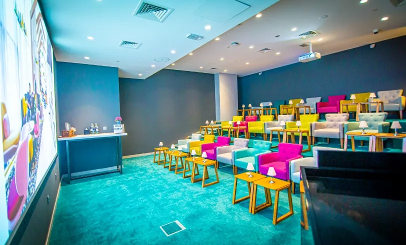 Private cinema with colourful chairs and a bright blue carpet.