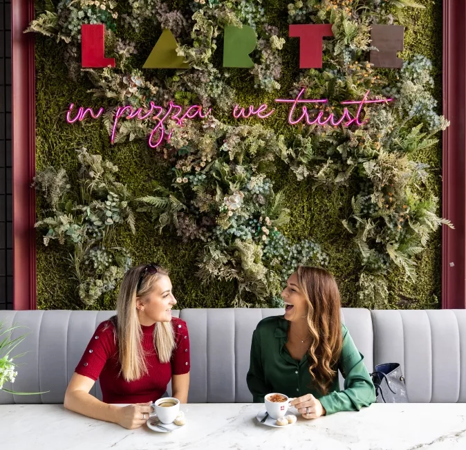 Two women enjoying a coffee sat at a table in the Larte restaurant.