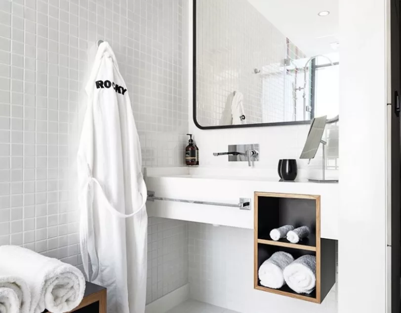 A bathroom with a mirror, white towels and a dressing gown.