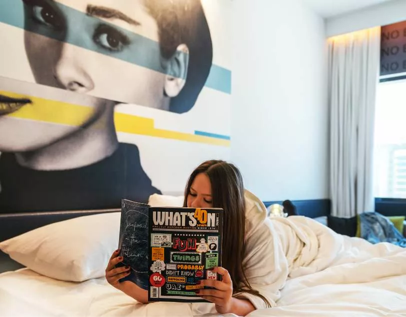 A girl reading a book whilst led on a bed.